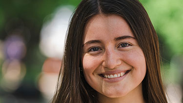 Smiling student in shaded trees