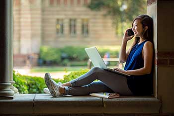 Student sitting on a ledge, calling on their phone