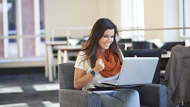 Student celebrating while working on a laptop