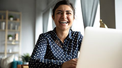 Student laughing while working on a laptop