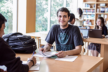 Student sitting at desk in library with other students