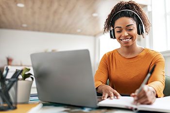 Student with headphones working at a laptop