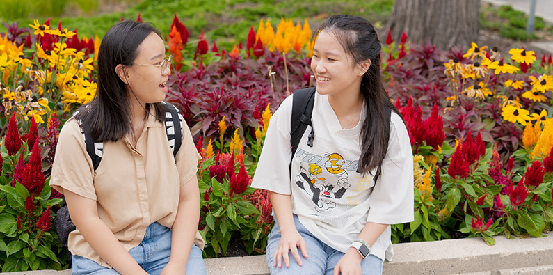Two students sitting by flowers