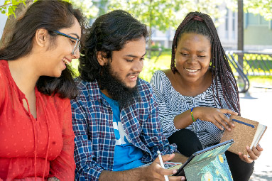 Three students looking at an iPad.