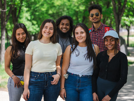 Five students standing outside and smiling at the camera.