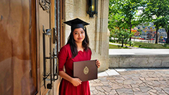 A photo of Irin in her University of Manitoba graduation gown and cap, holding her certificate