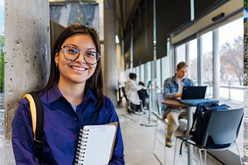 Photo of a student smiling while holding a notebook