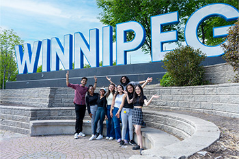 Photo of a group of students in front of a large sign that reads Winnipeg