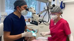 A photo of Po-Chen Lu in is dental scrub alongside another lady, also in a scrub working on a patient